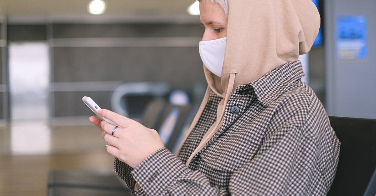 Woman in a face mask using her smartphone, sitting in an airport waiting area.