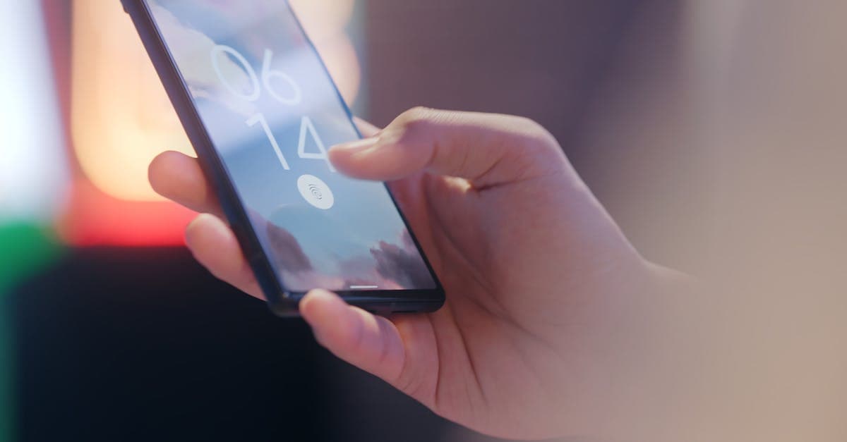 Close-up of a hand holding a smartphone locked with a fingerprint sensor.