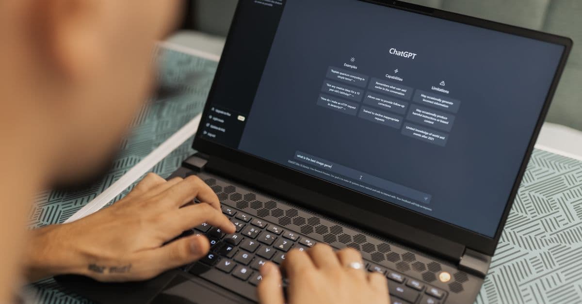 Close-up of a person typing on a laptop displaying the ChatGPT interface, emphasizing modern technology use.