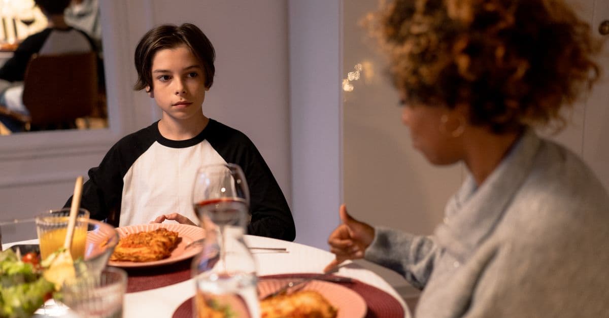 Family gathering around the dinner table enjoying pasta and drinks. Emotional connection and conversation.