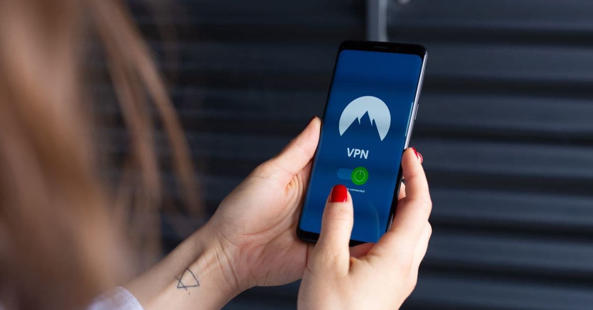 Close-up of a woman's hands using a VPN app on a smartphone, emphasizing digital security.