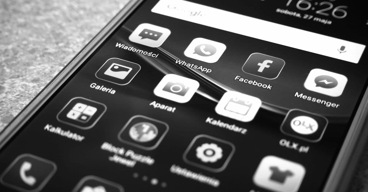 Black and white photo of smartphone showing popular app icons like Facebook and WhatsApp.