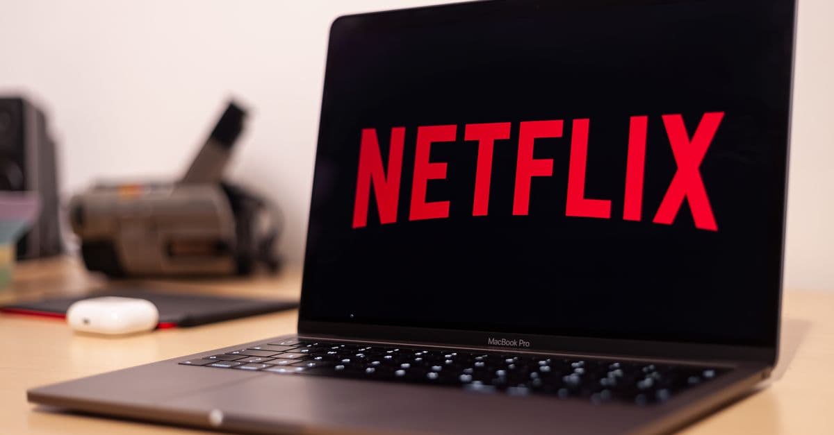 Close-up of a MacBook Pro showing Netflix on the screen in a modern workspace.
