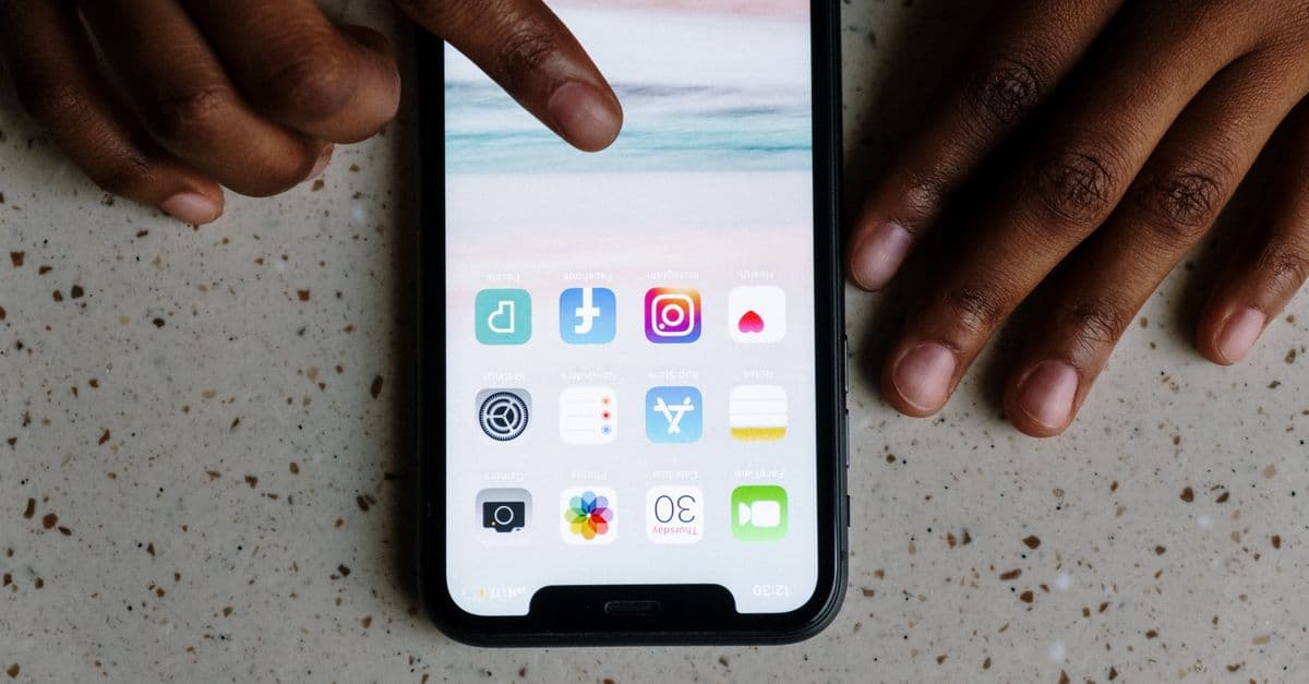Close-up view of hands interacting with social media apps on a smartphone screen.