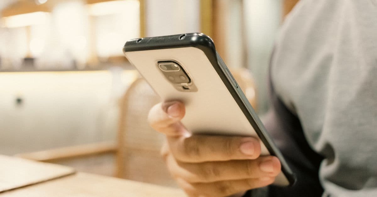 A person using a smartphone in a modern indoor setting, emphasizing technology.