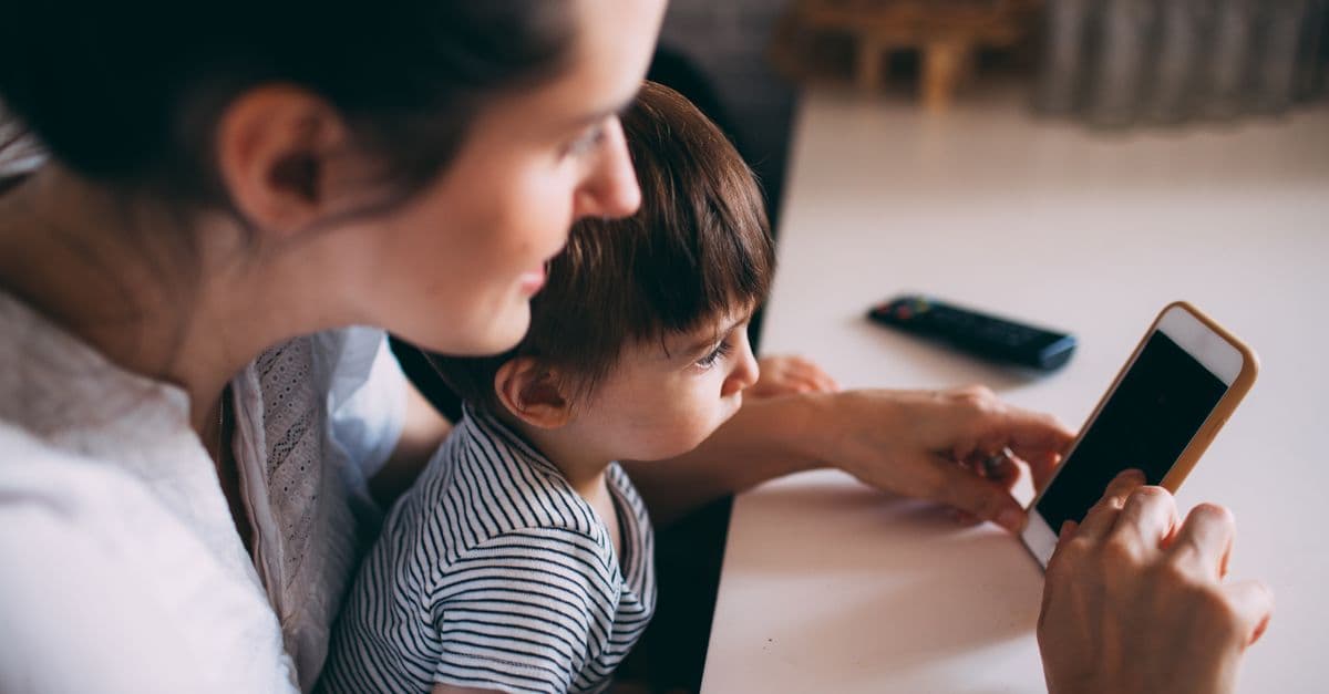 A mother and child bonding while using a smartphone at home.