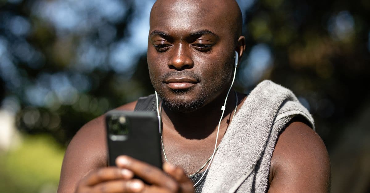 A man with earphones enjoying music on his smartphone while relaxing outdoors.