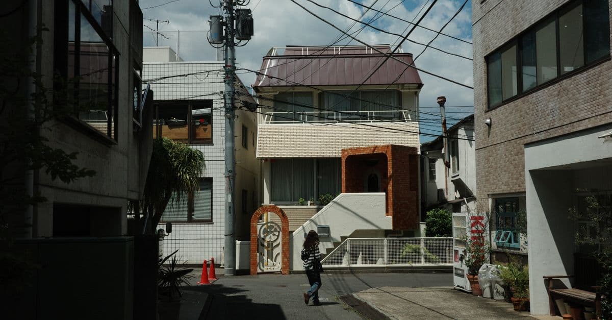 A street view in an urban Asian neighborhood with modern architecture and a person walking.