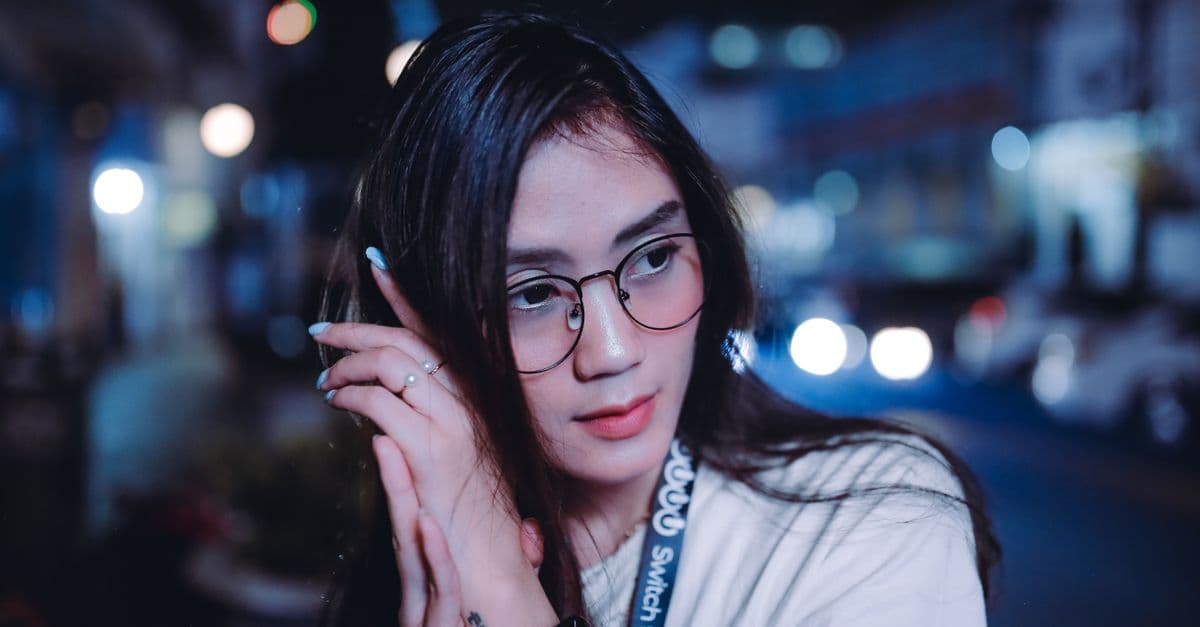 Beautiful woman wearing glasses with bokeh lights in urban night setting.