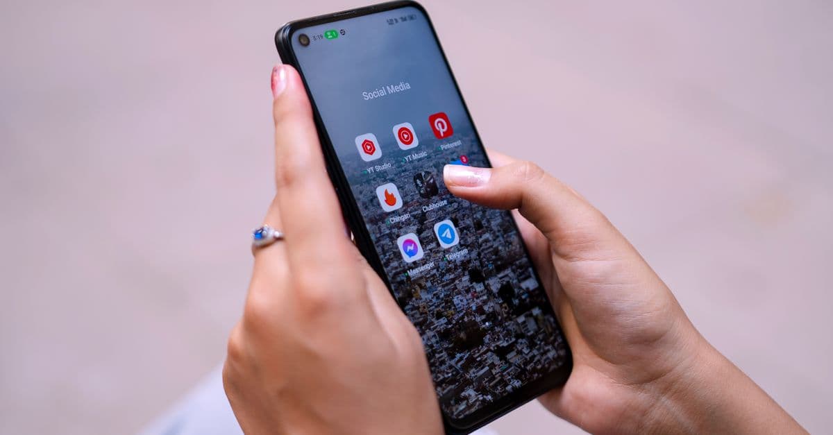 Close-up of hands holding a smartphone displaying social media apps, emphasizing digital connectivity.