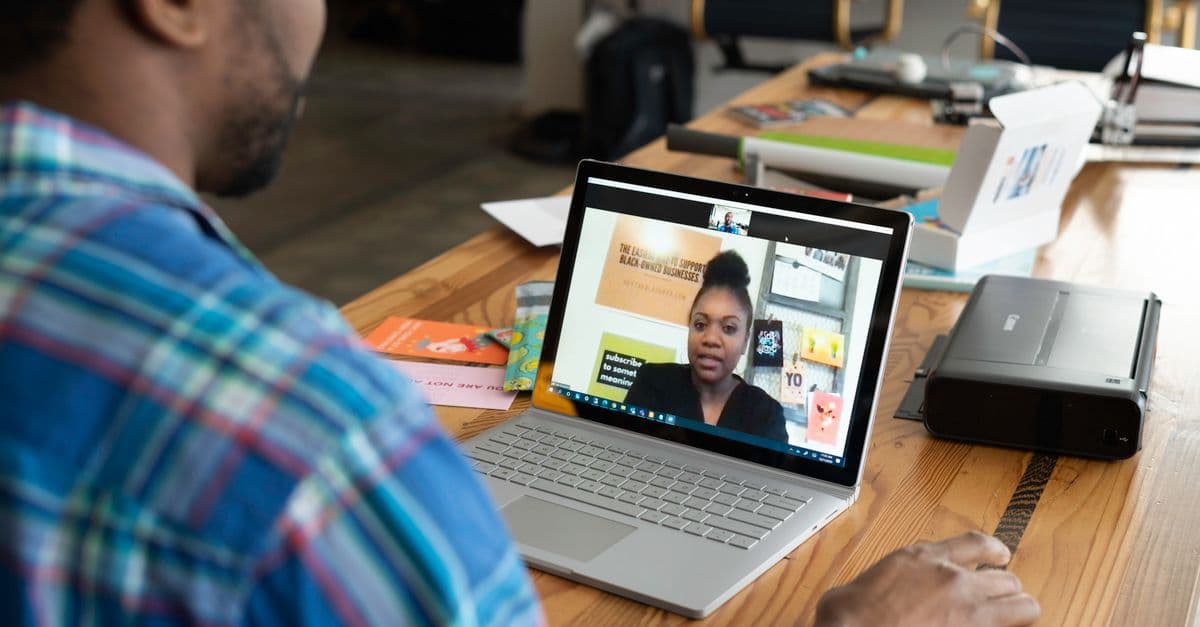 A businessman engaging in a virtual meeting using a laptop at an office desk.