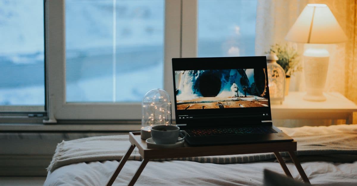 Relaxing bedroom scene with a laptop on a tray table, perfect for a cozy night in.