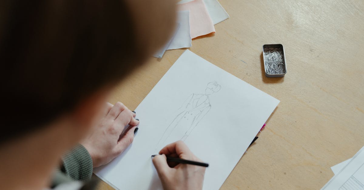 A person sketching fashion designs in a sewing workshop with fabric swatches and pins.