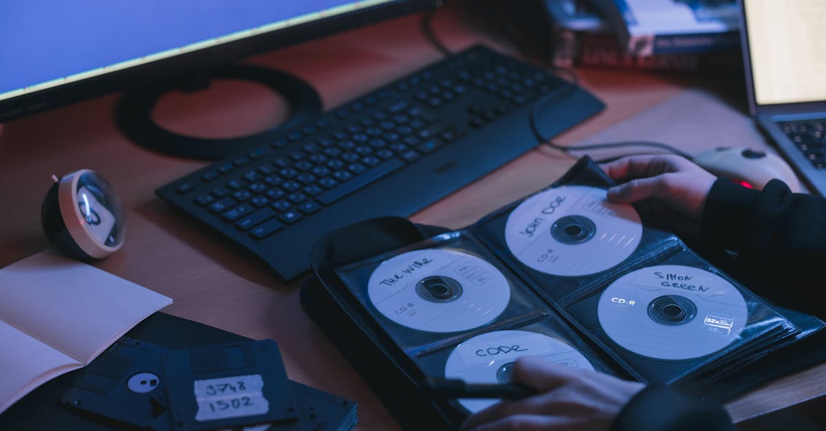 A close-up of CDs and disks on a desk, featuring hands in a tech environment.