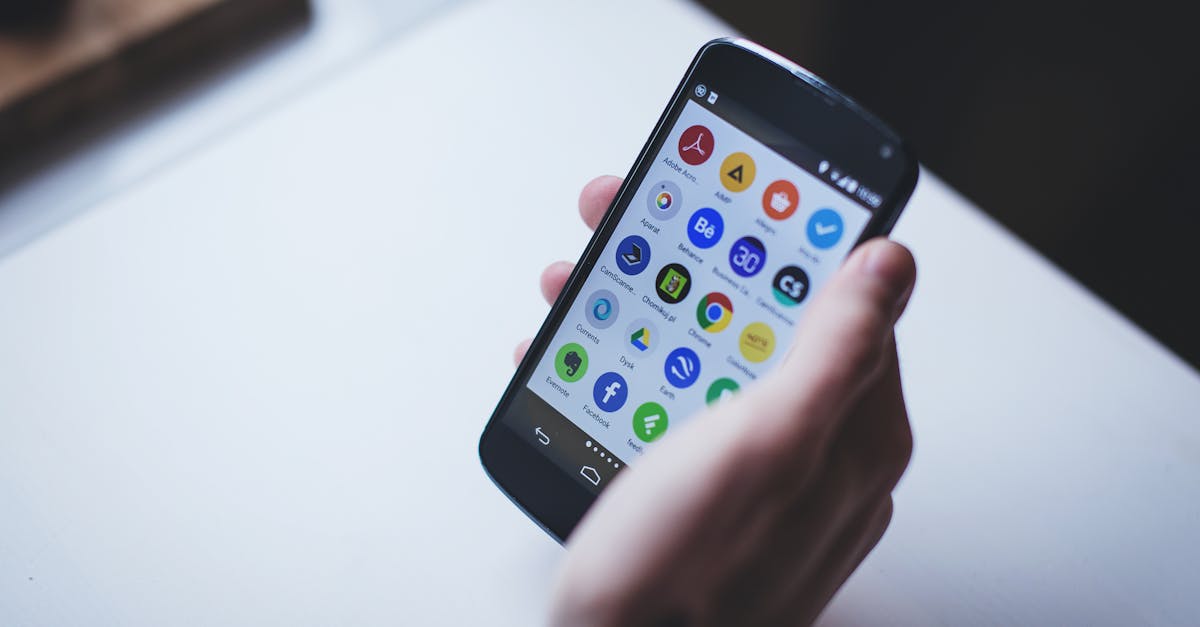 Close-up of a person holding a smartphone with various app icons visible on the screen.