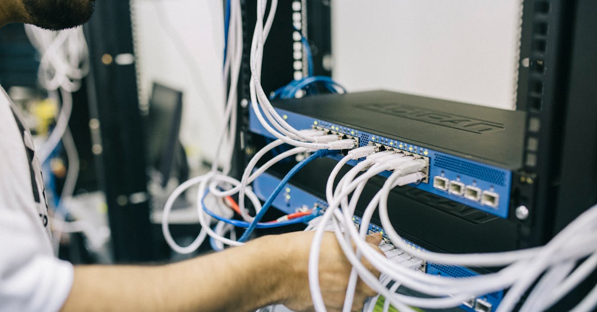 An IT professional configuring network cables in a server rack, focusing on Ethernet connections.