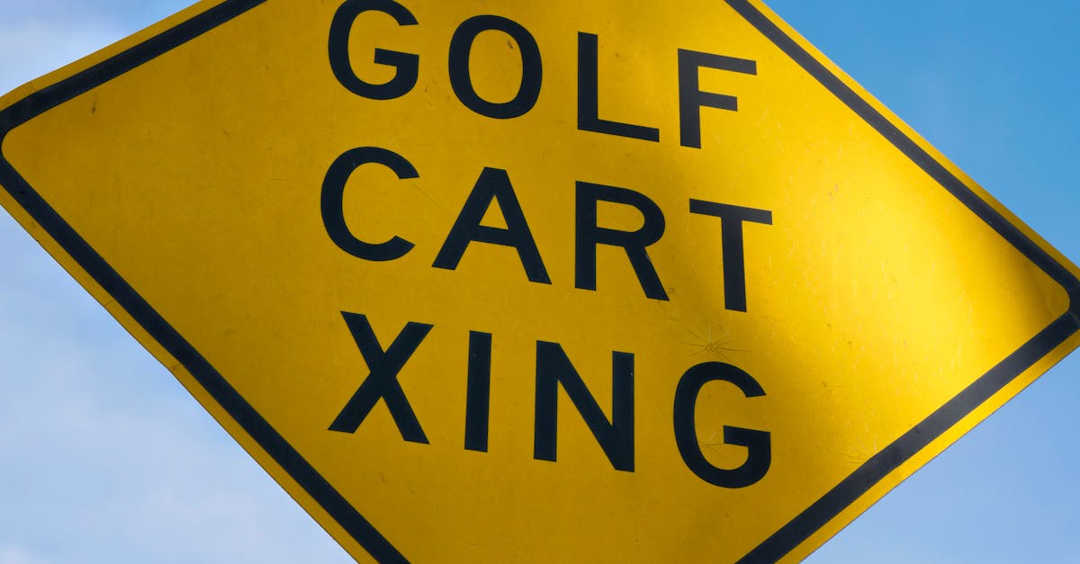 Close-up of a yellow golf cart crossing sign under clear blue skies, indicating a golfer's area.