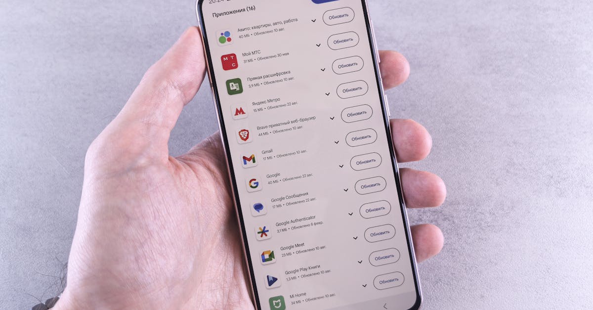 Close-up of a hand holding a smartphone displaying app updates on a light background.