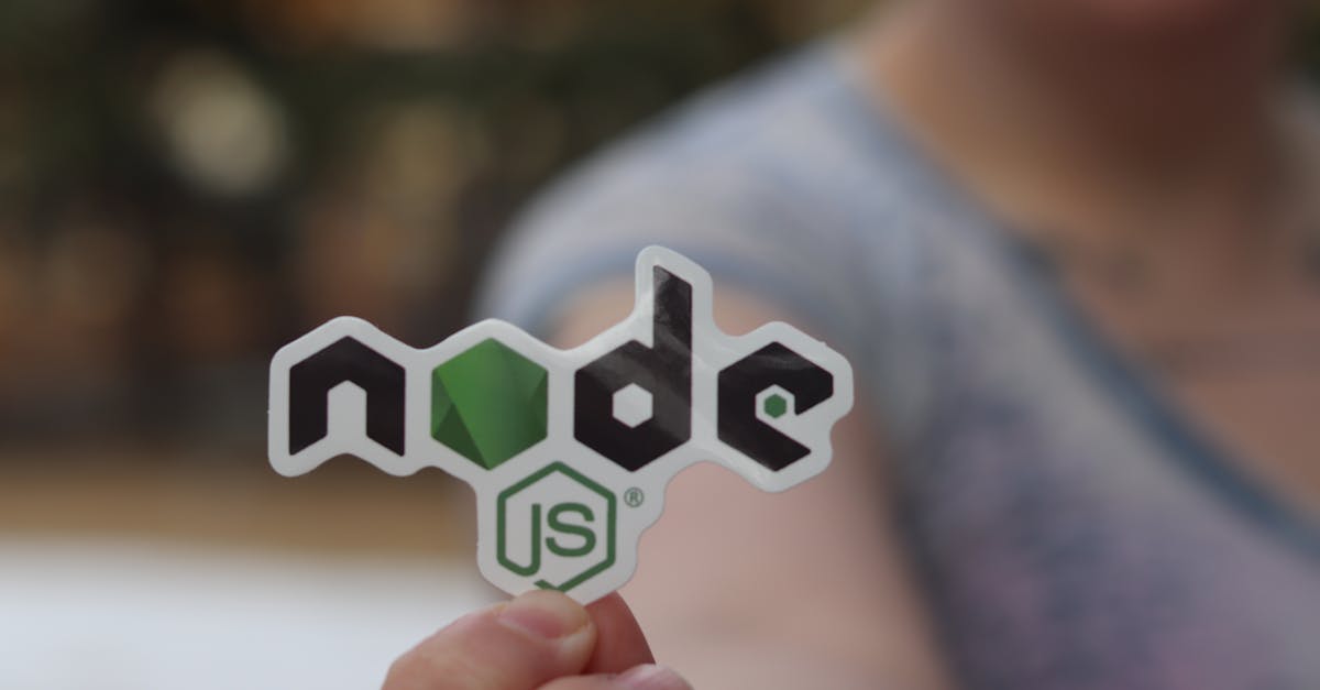 A person holding a Node.js sticker with a blurred background, close-up shot.