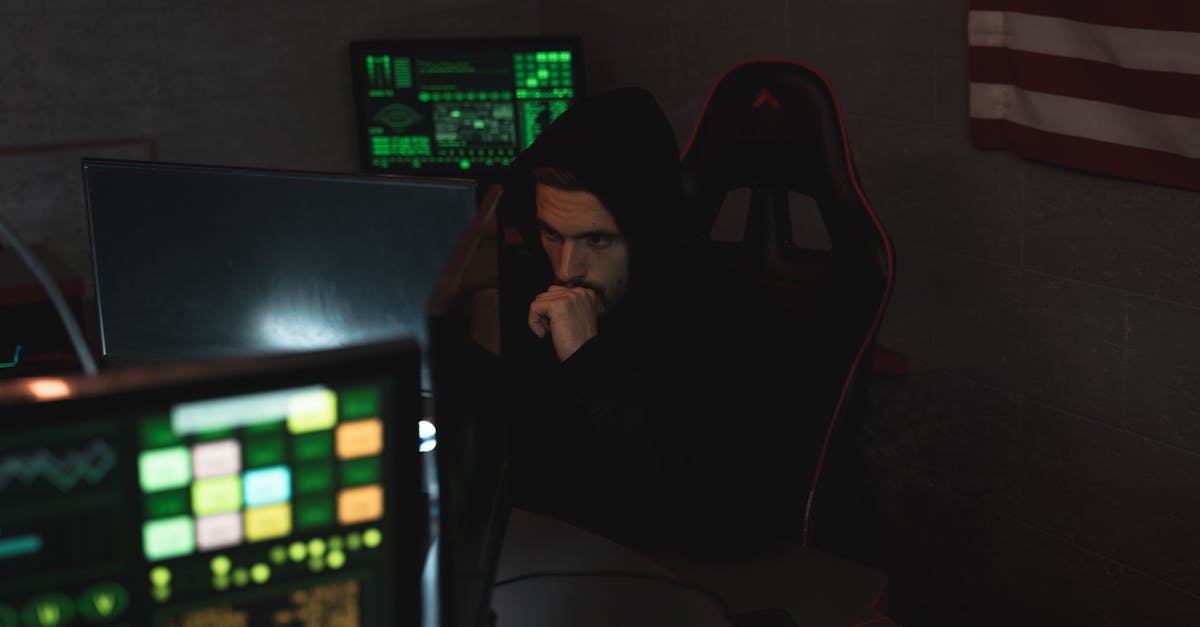 A cybersecurity expert monitors multiple screens, focused on data protection in a dark room.