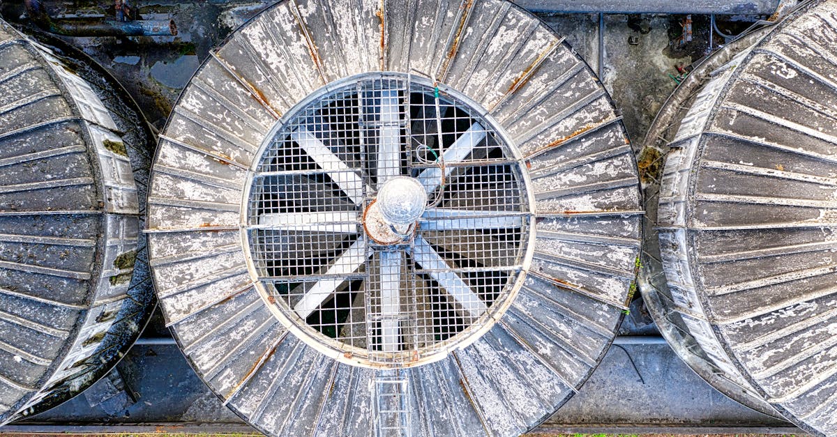 Drone top view of big shabby old metal ventilation fans on factory among pipes