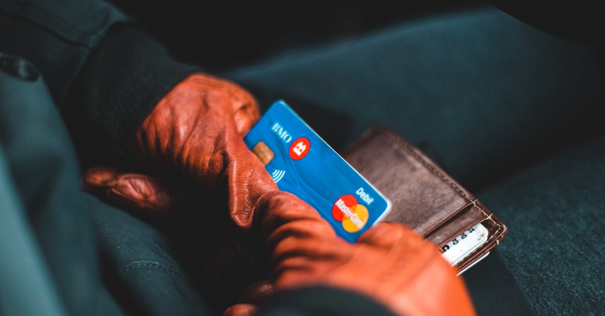 Close-up of hands in gloves holding a credit card and wallet indoors.