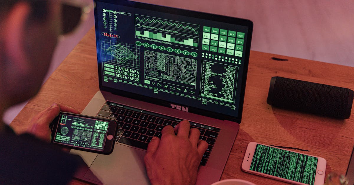 Man working with cybersecurity software on laptop and smartphone.