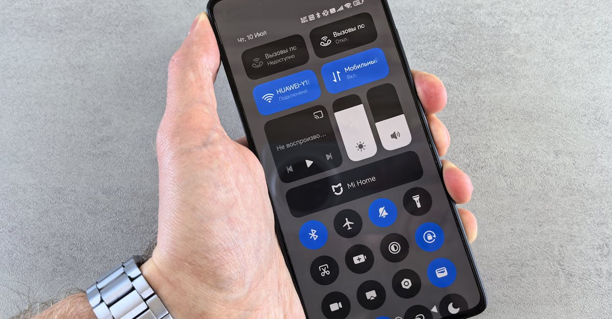 Close-up of a hand holding a smartphone displaying its control panel interface.
