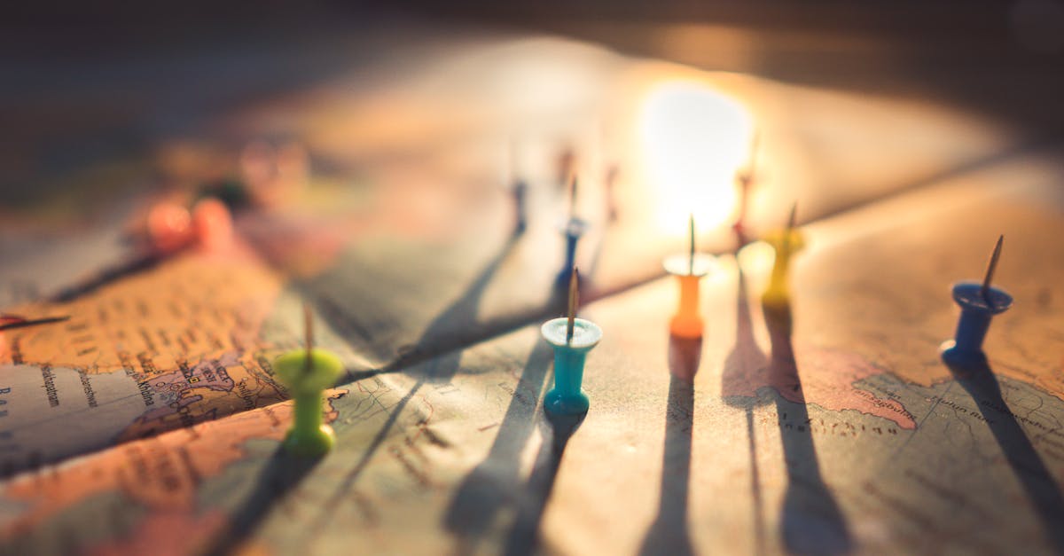 A close-up view of colorful push pins casting shadows on a world map during sunset, highlighting global travel.