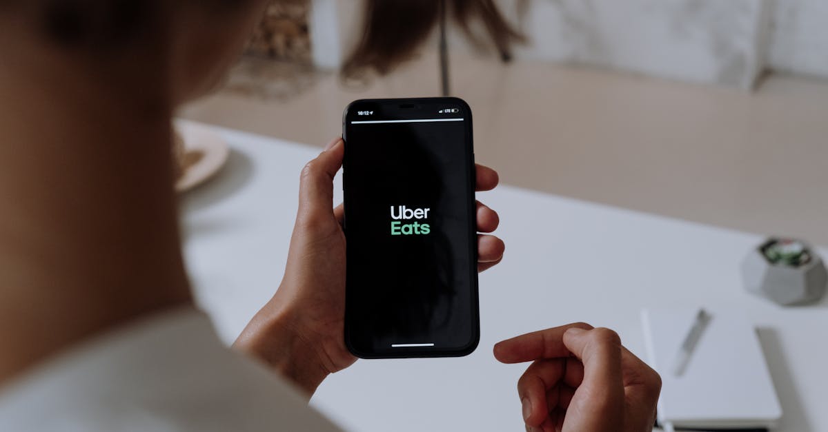 Person holding a smartphone using Uber Eats. Indoor setting with a clear view of the app interface.