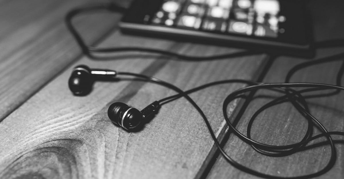 Monochrome image of earphones and smartphone on wooden table, showcasing a modern lifestyle.