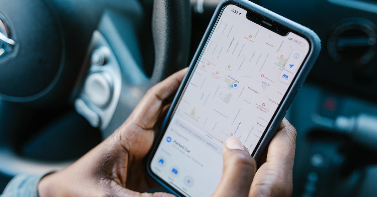 Close-up of hands holding a smartphone with GPS navigation displayed, in a car setting.