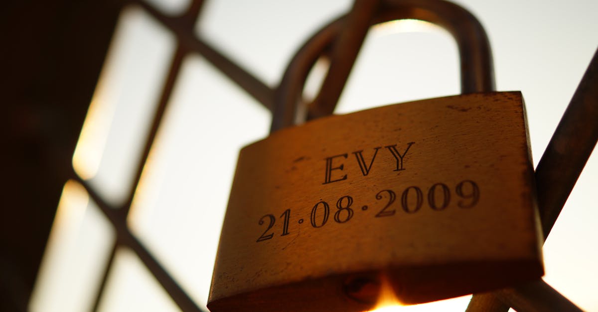 Golden padlock engraved with 'EVY 21.08.2009' on a fence, symbolizing love.