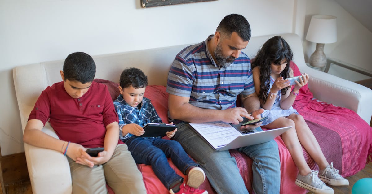 Father and children using gadgets on a sofa, balancing work and leisure.