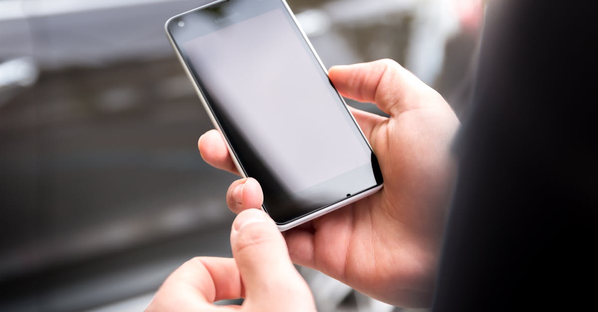Close-up of hands holding a smartphone outdoors during the day.