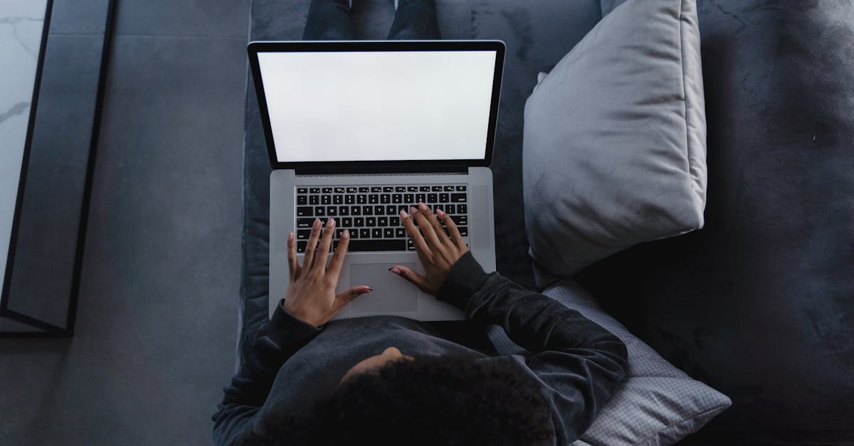 A person is using a laptop while sitting comfortably on a couch at home, viewed from above.