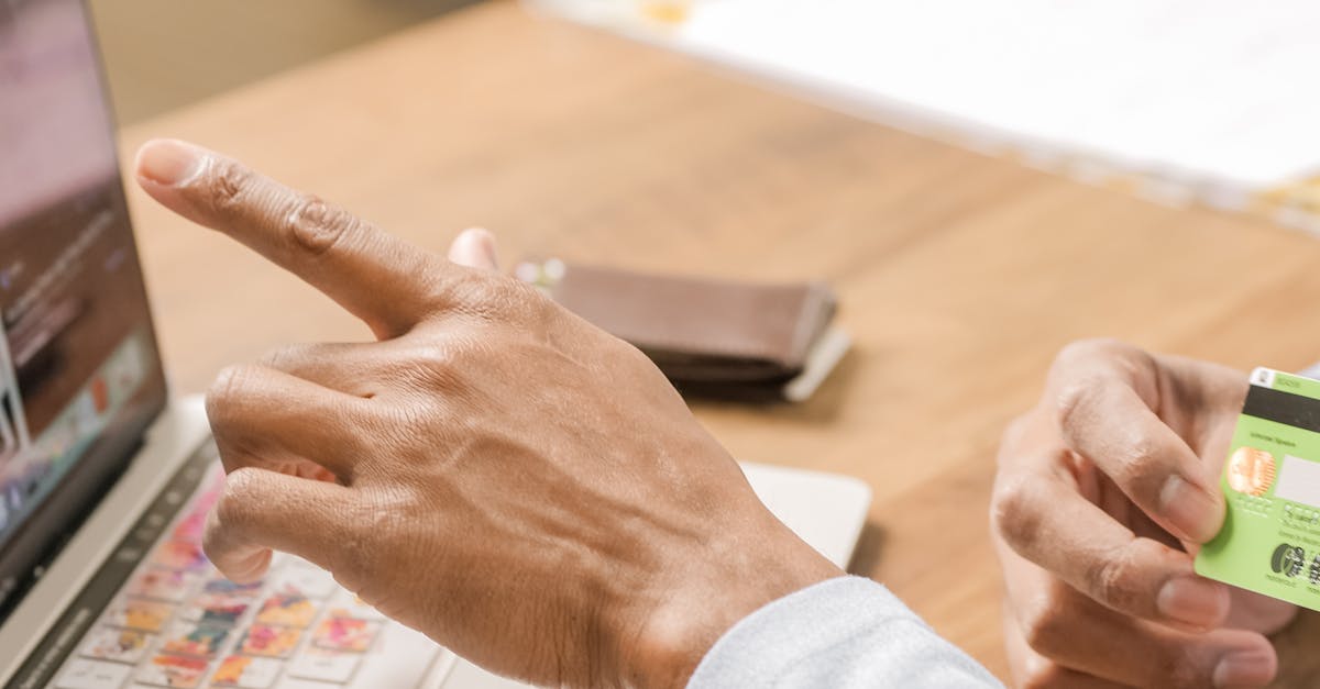 Person using a credit card and pointing at laptop for online shopping activity.