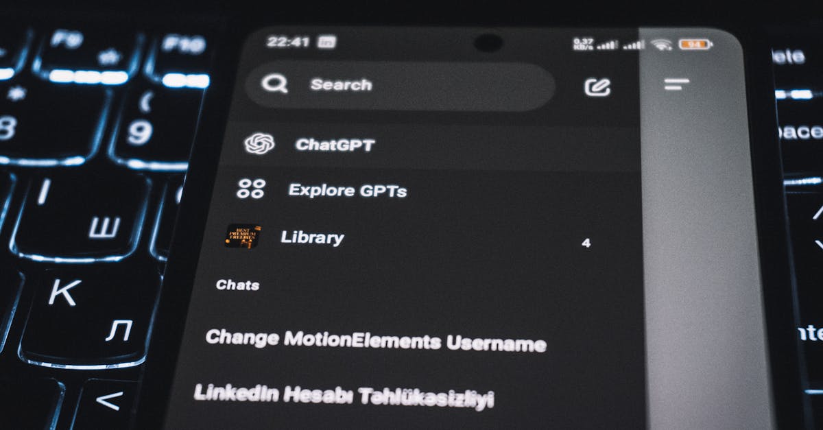 Close-up of a smartphone displaying a chat app interface with a backlit keyboard in the background.