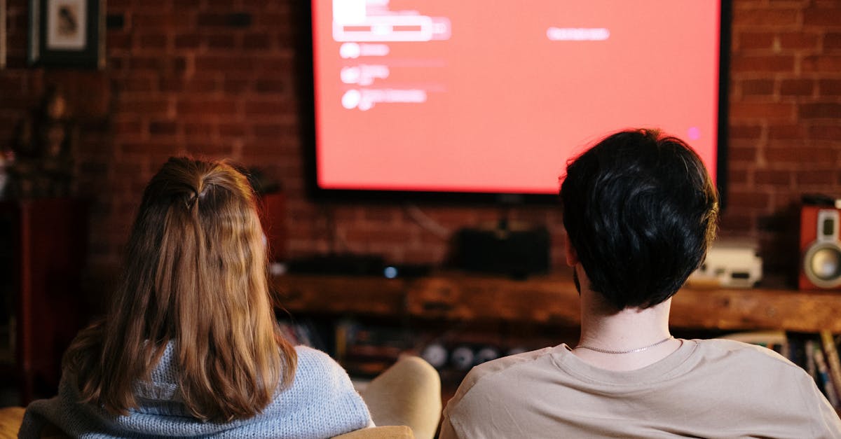 A couple watches TV together in a cozy brick-walled living room on a sofa.