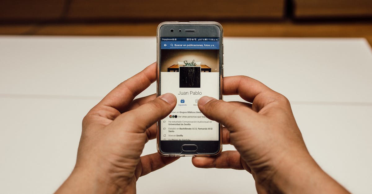 Close-up of hands using a smartphone with a social media page indoors.