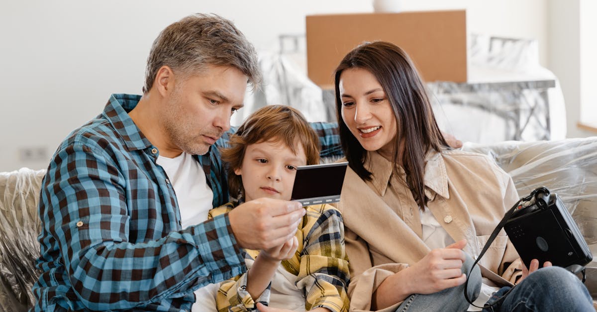 Happy family sitting on couch looking at instant photo in their new home.
