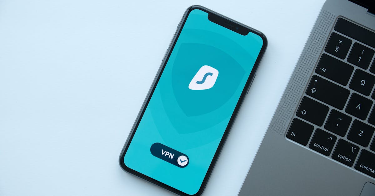 Flat lay of a smartphone showing a VPN app next to a laptop on a desk.
