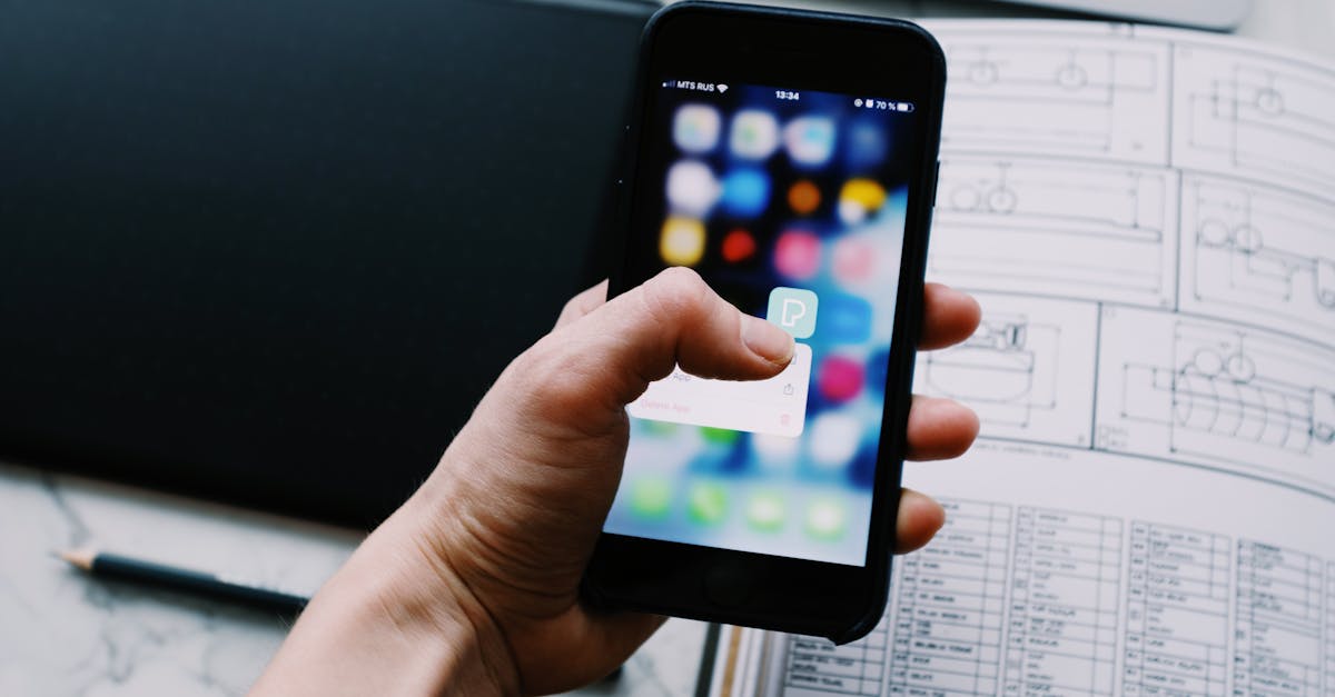 A hand holding a smartphone, showcasing a blurred app interface in an office setting.