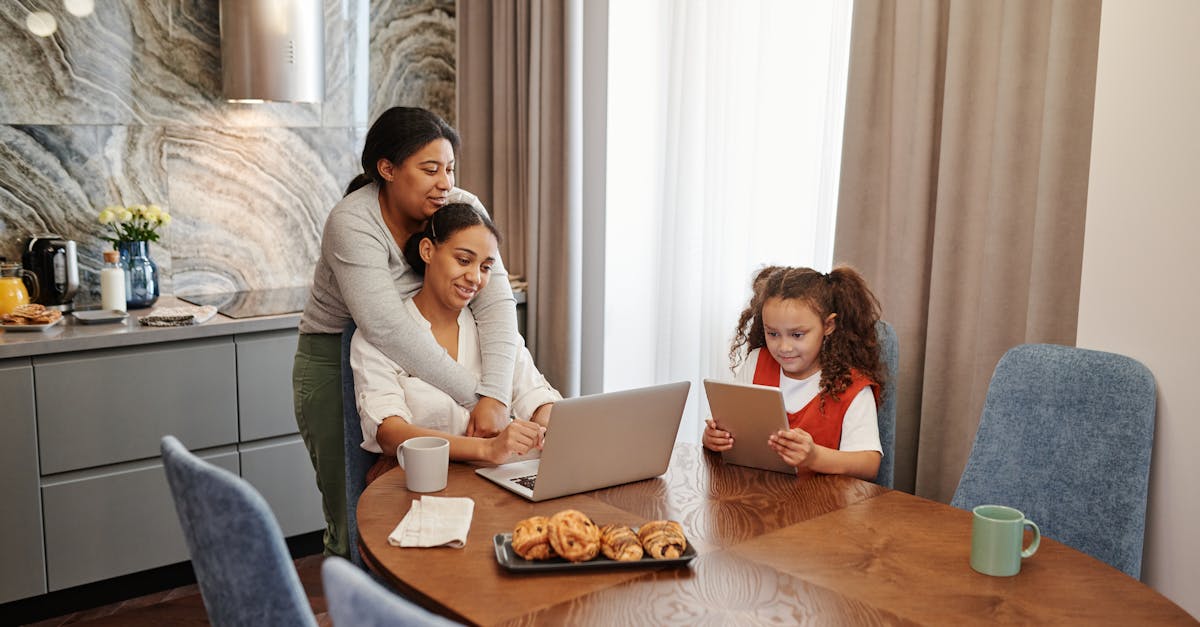 A loving family spends time together in a cozy kitchen, with a laptop and tablet.