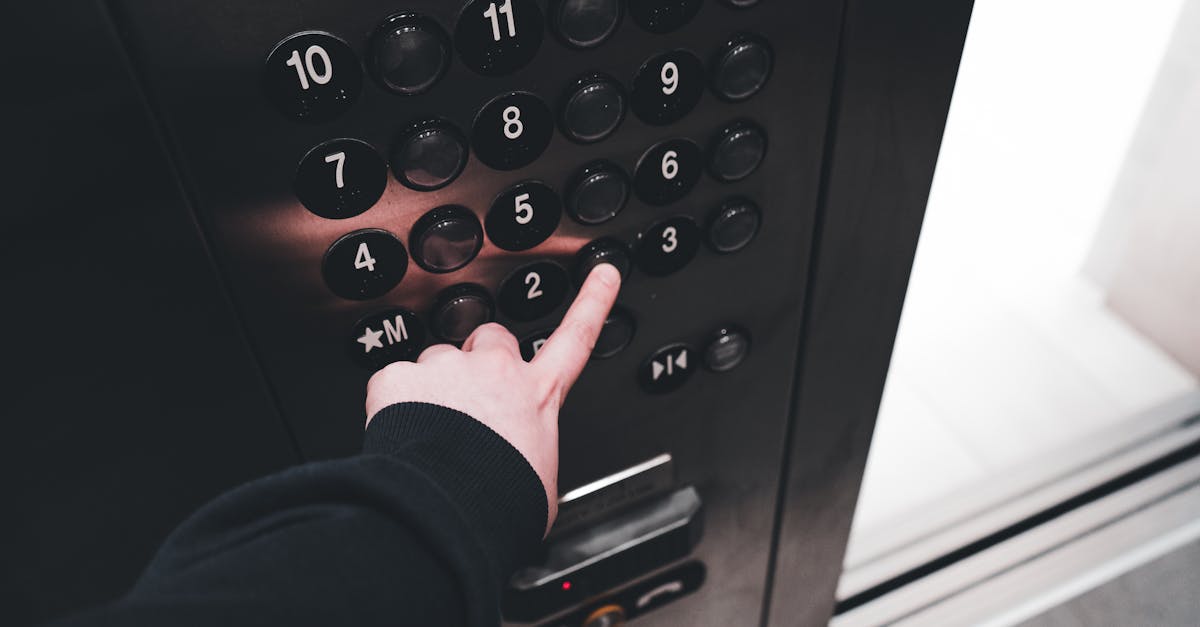 A person pressing the elevator button inside a modern elevator, showcasing the control panel with floor numbers.