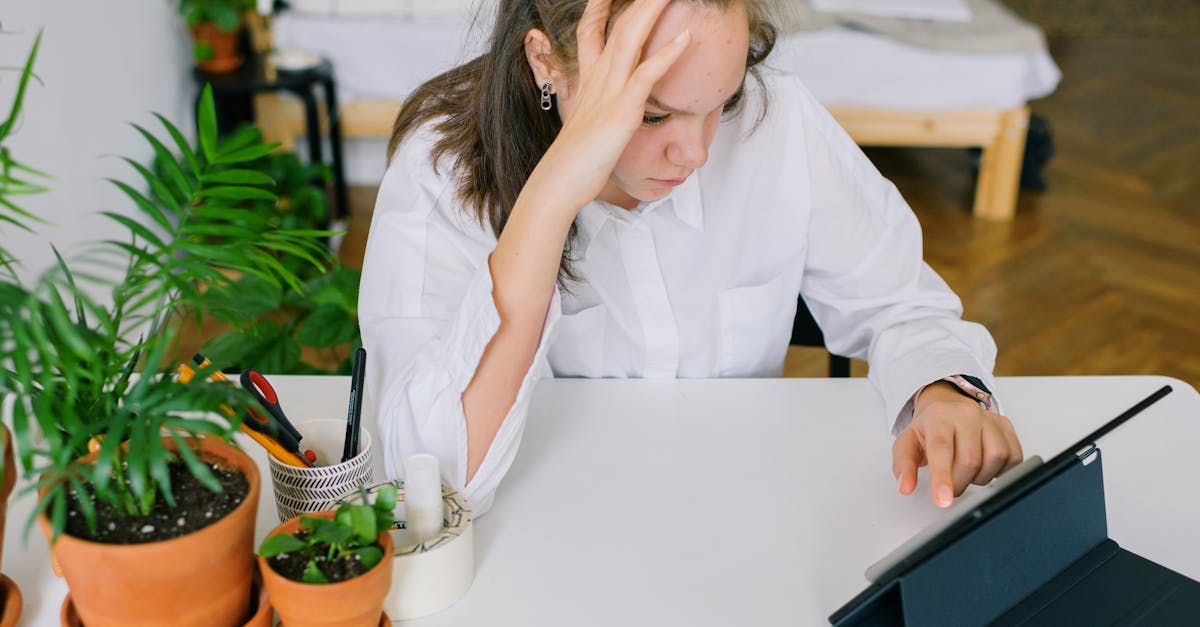 Young woman in white shirt using tablet in home office with plants.