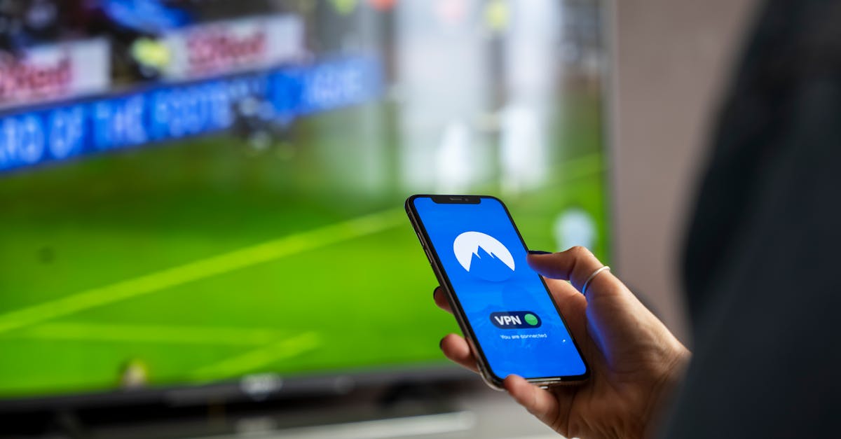 Close-up of a person holding a smartphone with a VPN app, streaming sports on TV.